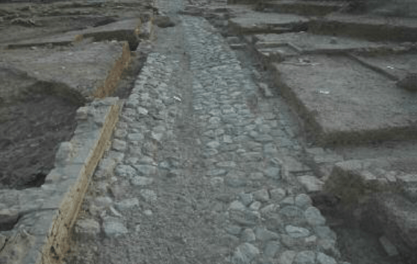 Eski bir yapının kalıntıları arasında yer alan taş döşeli bir yol.