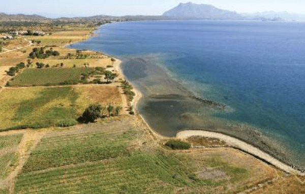 Aerial view of a coastal landscape featuring fields and a blue sea.